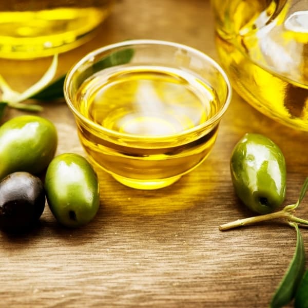 photo of a glass dish of olive oil with olives around it representing Melgarejo Hojiblanca Extra Virgin Olive Oil