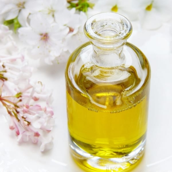 photo of jar of olive oil and pink flowers representing sevillano extra virgin olive oil