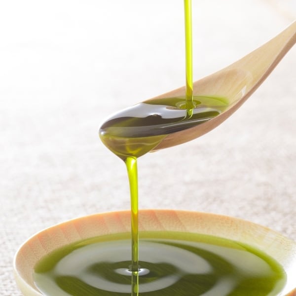 photo of wood spoon pouring olive oil into bowl representing organic chemlali extra virgin olive oil