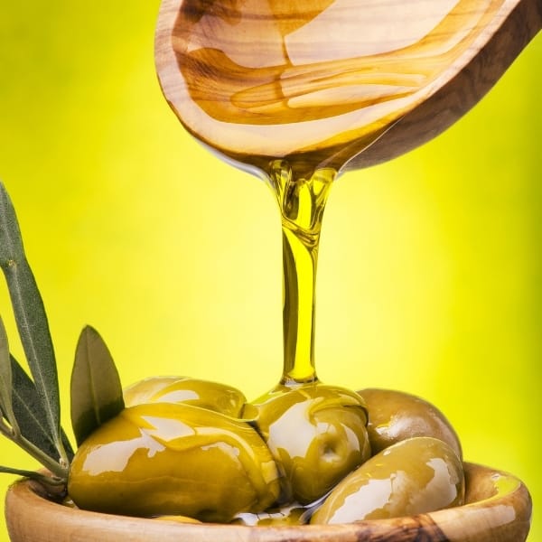 photo of wood spoon pouring olive oil onto olives in bowl representing Don Carlo extra virgin olive oil