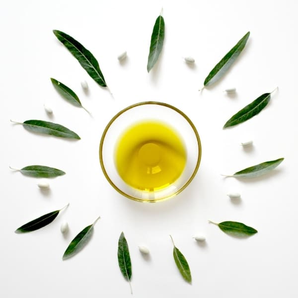 photo of dish with olive oil surrounded by leaves representing Italian blend extra virgin olive oil