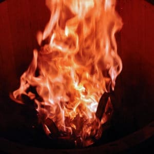 photo of wood barrel on fire representing olive wood smoked flavored olive oil
