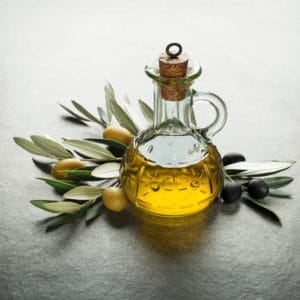 photo of jar of olive oil with olives and olive branches representing melgarejo picual extra virgin olive oil