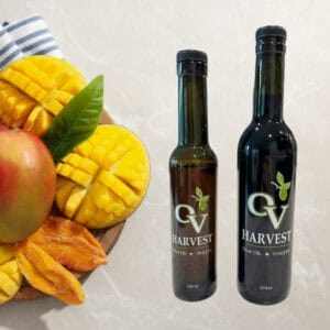 A mango, sliced mango and OV Harvest balsamic vinegar bottles representing Mango White Balsamic Vinegar