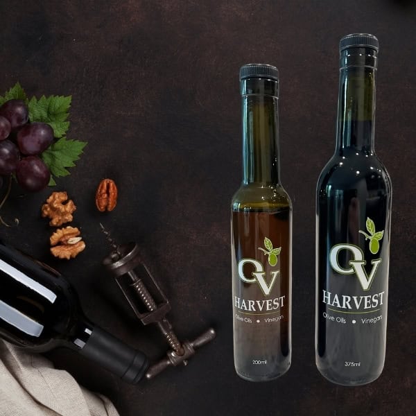 Bottle of wine, grapes, walnuts, wine opener and bottles of OV harvest balsamic vinegar representing Denissimo Balsamico