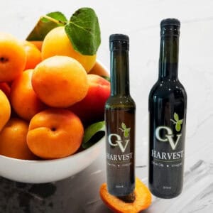 Bowl of apricots and OV Harvest balsamic vinegar bottles representing Blenheim Apricot White Balsamic Vinegar