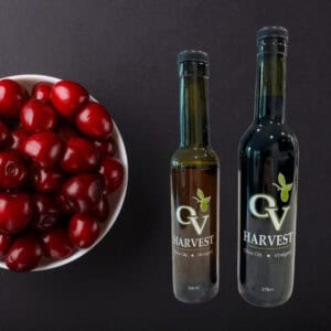 Bowl of cherries and OV Harvest balsamic vinegar bottles representing Black Cherry Balsamic Vinegar