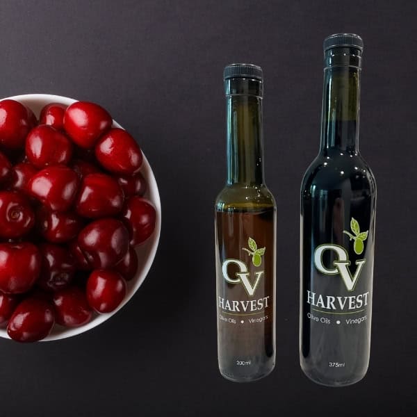 Bowl of cherries and OV Harvest balsamic vinegar bottles representing Black Cherry Balsamic Vinegar