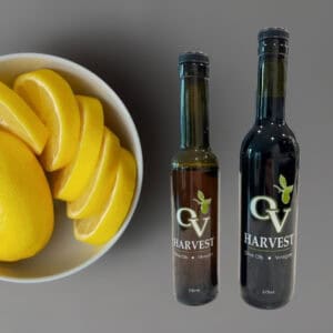 Bowl of lemons and OV Harvest balsamic vinegar bottles on a gray background representing Sicilian Lemon White Balsamic Vinegar