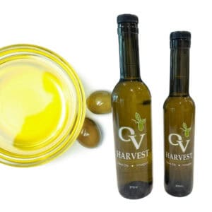 Bowl of olive oil with two olives and OV Harvest olive oil bottles representing Arbosana Extra Virgin Olive Oil