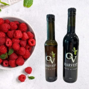 Bowl of raspberries and OV Harvest balsamic vinegar bottles representing Raspberry Balsamic Vinegar