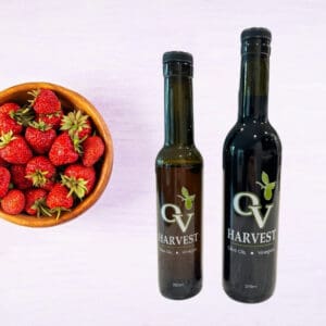 Bowl of strawberries and OV Harvest balsamic vinegar bottles representing Strawberry Balsamic Vinegar