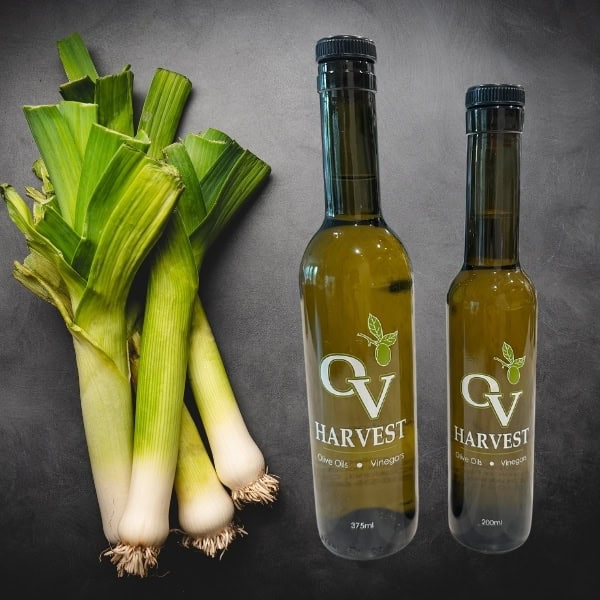 Bunch of leeks and OV Harvest olive oil bottles representing Leek Olive Oil