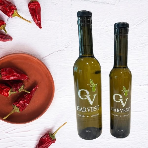 Chipotle peppers in a bowl and OV Harvest olive oil bottles representing Chipotle Olive Oil