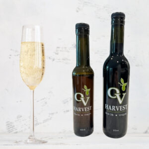 Glass of champagne and OV Harvest vinegar bottles representing Champagne Vinegar