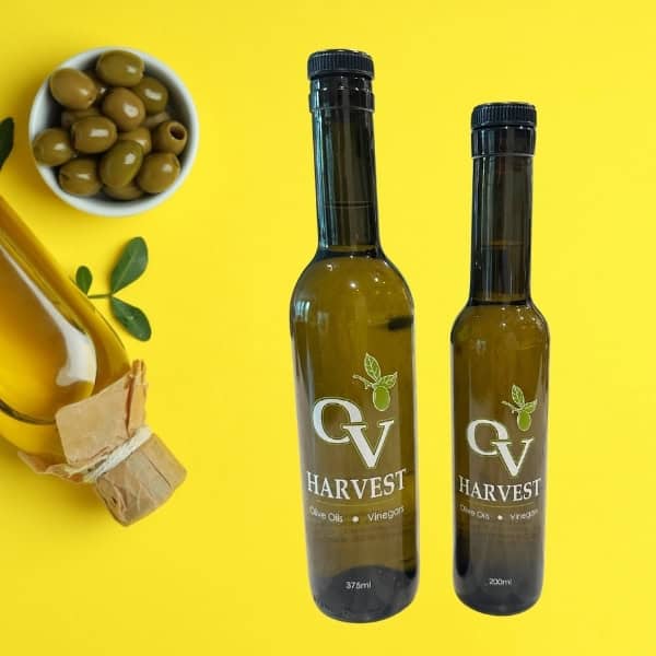 Green olives in a dish, a bottle of olive oil and OV Harvest olive oil bottles representing Cerasuola Extra Virgin Olive Oil