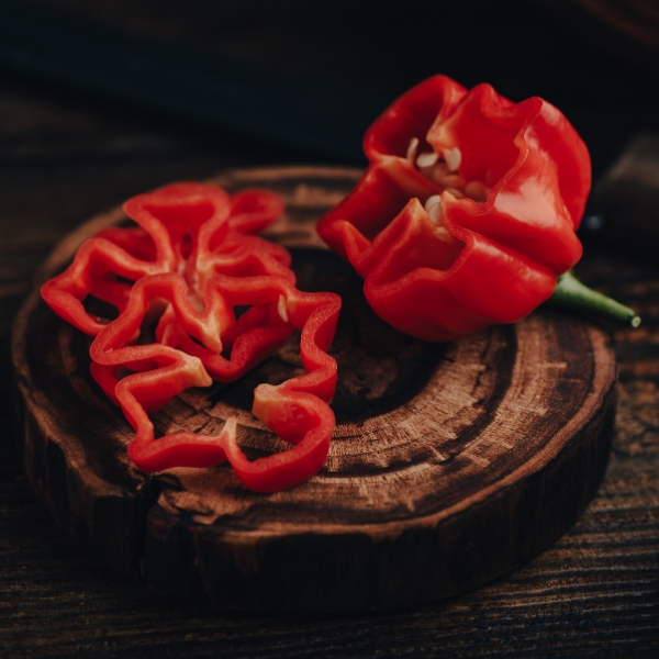 Wood bowl with a sliced habanero pepper on it representing Habanero Whole Pepper Fused Olive Oil.