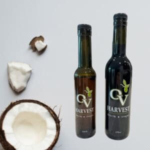 Half of a coconut, pieces of coconut and OV Harvest balsamic vinegar bottles representing Coconut White Balsamic Vinegar