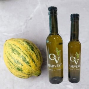 Image of a green lemon next to bottles of OV Harvest Olive Oil representing Green Lemon Olive Oil