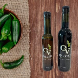 Jalapeños in a bowl and OV Harvest balsamic vinegar bottles representing Jalapeño White Balsamic Vinegar