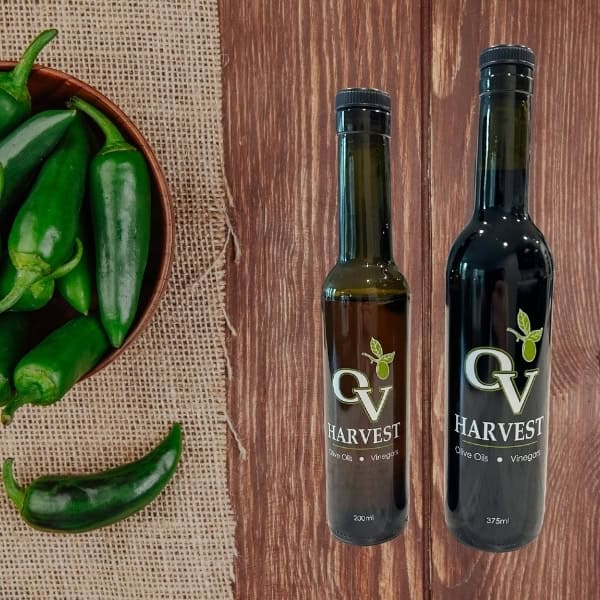 Jalapeños in a bowl and OV Harvest balsamic vinegar bottles representing Jalapeño White Balsamic Vinegar