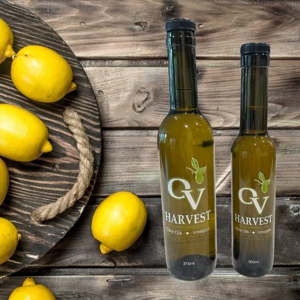 Lemons on a wood board and OV Harvest olive oil bottles representing Portuguese Lemon Olive Oil