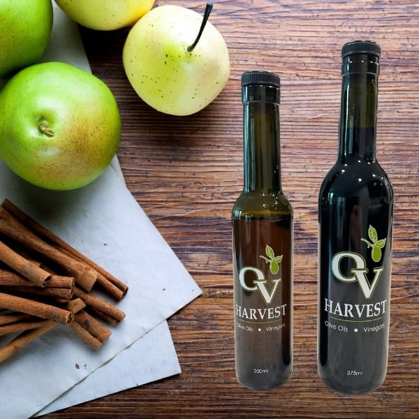 Pears and cinnamon sticks and OV Harvest balsamic vinegar bottles on a wood background representing Cinnamon-Pear Balsamic Vinegar