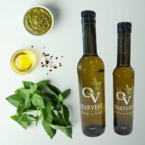 Pesto dish, olive oil dish, spices, basil leaves and OV Harvest olive oil bottles representing Spicy Calabrian Pesto Olive Oil