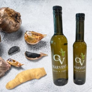 Pieces of black garlic and ginger and OV Harvest olive oil bottles representing Ginger & Black Garlic Olive Oil