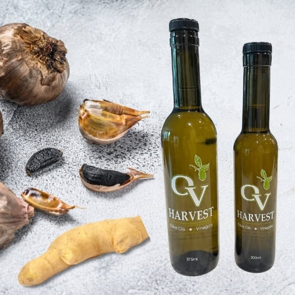 Pieces of black garlic and ginger and OV Harvest olive oil bottles representing Ginger & Black Garlic Olive Oil