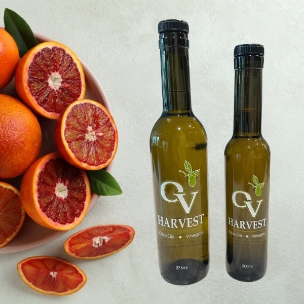 Plate with blood oranges and OV Harvest olive oil bottles representing Blood Orange Olive Oil