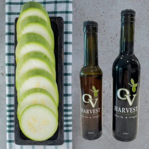 Sliced cucumber on a tray and OV Harvest vinegar bottles representing Suyo Cucumber White Balsamic Vinegar