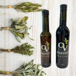 Sprigs of bundled herbs and bottles of OV Harvest balsamic vinegar representing Neapolitan Herb Balsamic Vinegar