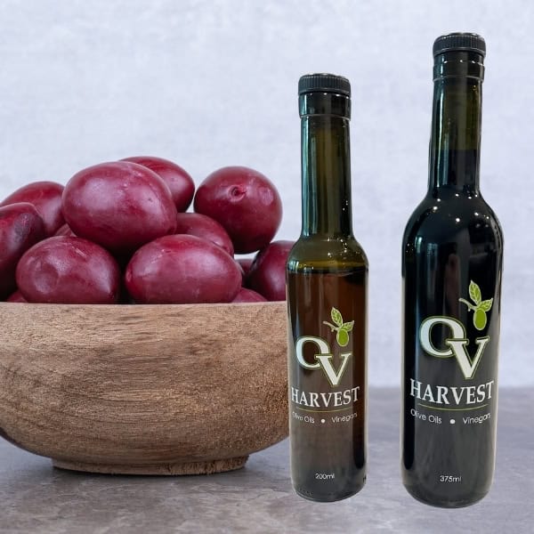 Umeboshi Plums in a wooden bowl and OV Harvest vinegar bottles representing Umeboshi Plum White Balsamic Vinegar