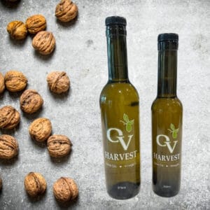 Walnuts on a stone table and OV Harvest oil bottles representing Roasted Walnut Oil