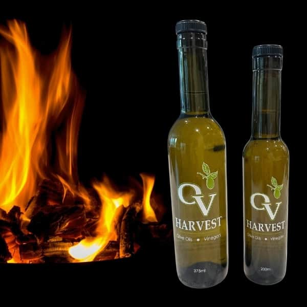 Wood fire and OV Harvest olive oil bottles representing Olive Wood Smoked Olive Oil