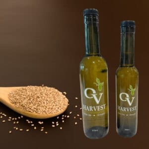 Wood spoon with sesame seeds and OV Harvest oil bottles representing Japanese Sesame Oil
